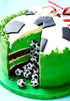 the cake is decorated with soccer balls and green frosting on it's side