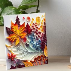 a painting of autumn leaves and berries on a white background art board with a plant next to it