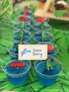 there are many cups with blue liquid in them on the table and one has a name tag that says dino silly