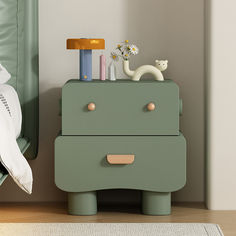 a nightstand with two drawers on top of it next to a green chair and bed