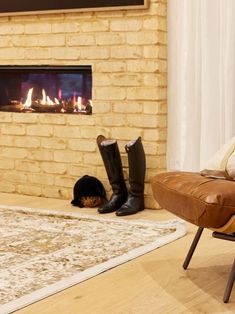 a living room with a fire place and two boots sitting on the floor in front of it