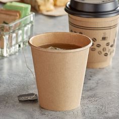 two coffee cups sitting on top of a table next to a spoon and cup holder