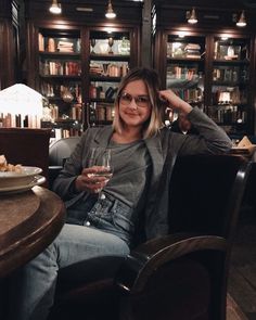 a woman sitting at a table with a glass of wine