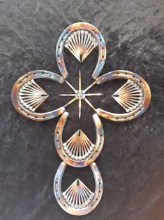 a cross made out of metal on top of a black surface with an arrow in the center