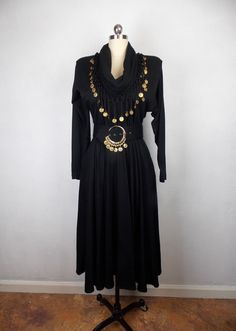 "Vintage 1990's black dress with cowl neck, elastic waist, pockets, cowl neckline, and matching belt. Uniquely embellished with faux gold coins. Removable shoulder pads.  Very good vintage condition. Label: Sybil California 80% Orlon, 20% wool Size: 4 Length 45\" Shoulders 15\"  Sleeves 23\" Bust 34\" Waist 24\"/26\" Hips open *Please note that vintage clothing and contemporary sizes can vary greatly. We take measurements of listed garments by laying the garment flat and then doubling the measurement. When considering whether a garment would fit, we suggest taking a similar garment from your own wardrobe and measure it lying flat as we do. Then compare the measurements." Goth Prom Dress, 1960s Cocktail Dress, Sequin Sleeve, Sweetheart Prom Dress, Skirt And Top Set, Glitter Dress, Cowl Neckline, Sheer Dress, Gold Coins