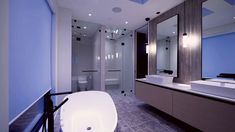 a modern bathroom with blue walls and white counter tops, an oval shaped bathtub in the foreground