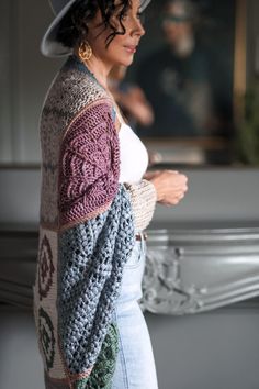 a woman wearing a hat and sweater standing in front of a mirror with her hands on her hips