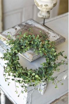 a wreath is sitting on top of an old chest with some greenery in it