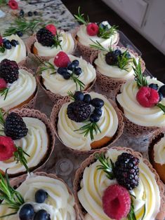 cupcakes with white frosting and fresh berries on top sit on a tray