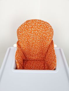 an orange chair sitting on top of a white table