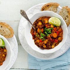 two bowls of chili with bread on the side