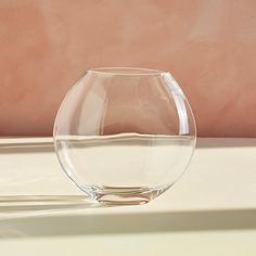 a clear glass bowl sitting on top of a white table next to a pink wall