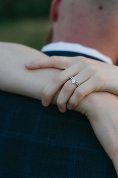 a close up of a person wearing a ring on their finger and holding the other hand