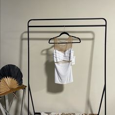 a clothes rack with a white shirt hanging on it and a fan next to it