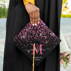 a woman holding a graduation cap with pink and purple confetti sprinkles on it