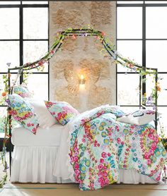 a bed with flowers on it in front of a window and a light fixture hanging from the ceiling