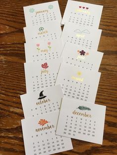 four calendars with different designs on them sitting on top of a wooden table next to each other