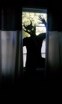 the silhouette of a deer standing in front of a window with its head sticking out