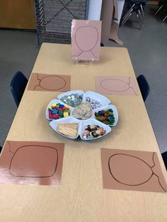 a wooden table topped with a plate filled with food next to cut out shapes on paper