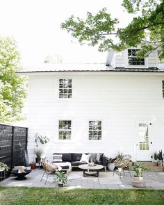 a white house sitting on top of a lush green field next to a yard filled with furniture