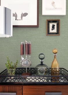 a table topped with vases and pictures next to a wall covered in framed art