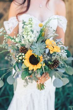 a bride holding a bouquet of sunflowers and greenery