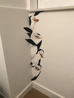 a group of penguins hanging from the side of a white wall next to a door