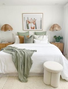 a bedroom with white bedding and green pillows