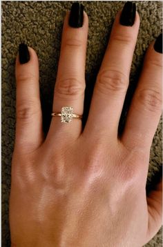 a woman's hand with black nails and a gold ring on her left wrist