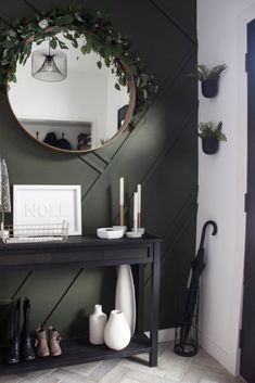 a black console table with white vases on it and a round mirror above it