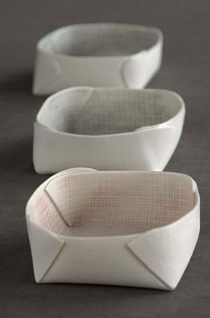 three white bowls sitting side by side on a gray surface with one empty bowl in the middle