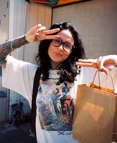 a woman with long hair and glasses holding up her hand