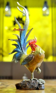 a colorful rooster figurine sitting on top of a wooden table