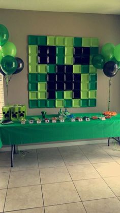 a green table with balloons and pictures on the wall behind it, in front of a checkerboard backdrop