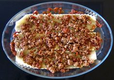 a glass bowl filled with food on top of a black countertop next to a knife and fork