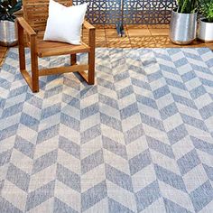 a wooden bench sitting on top of a blue and white rug next to potted plants