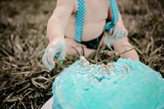 a baby sitting in the grass with a blue cake