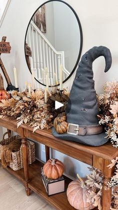 a wooden table topped with lots of pumpkins and other decorations next to a mirror