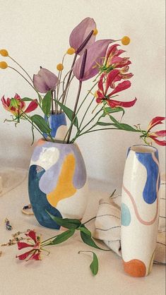 three vases with flowers in them sitting on a table next to other items and decorations