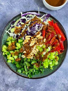 a bowl filled with salad and dressing next to a cup of coffee