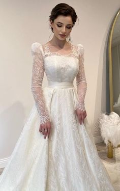 a woman in a white wedding dress standing next to a mirror