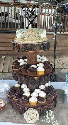 three tiered cake with cupcakes sitting on top of it in front of a bench