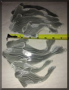 several fish shaped glass pieces next to a ruler