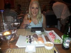 a woman sitting at a table with food and drinks