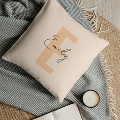 a personalized pillow on a blanket next to a candle and an open book with the letter f