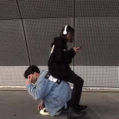 a man sitting on the ground with his headphones in his ears while looking at his cell phone