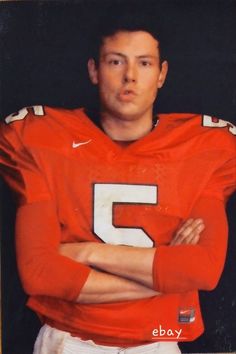 a man in an orange football uniform with his arms crossed and looking at the camera