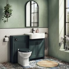 a bathroom with a toilet, sink and mirror in it's center wall is painted green