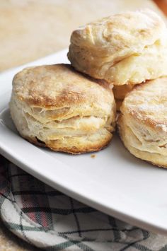 four biscuits on a white plate sitting on a table