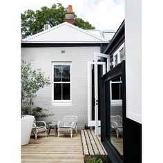 a white house with black trim and wooden decking